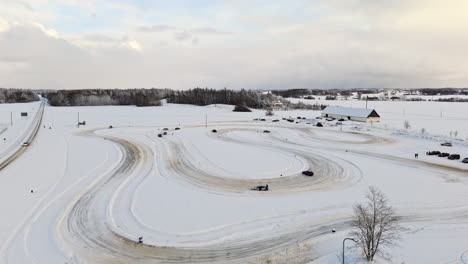 aerial view rising around cars driving on a rural ice track, winter day