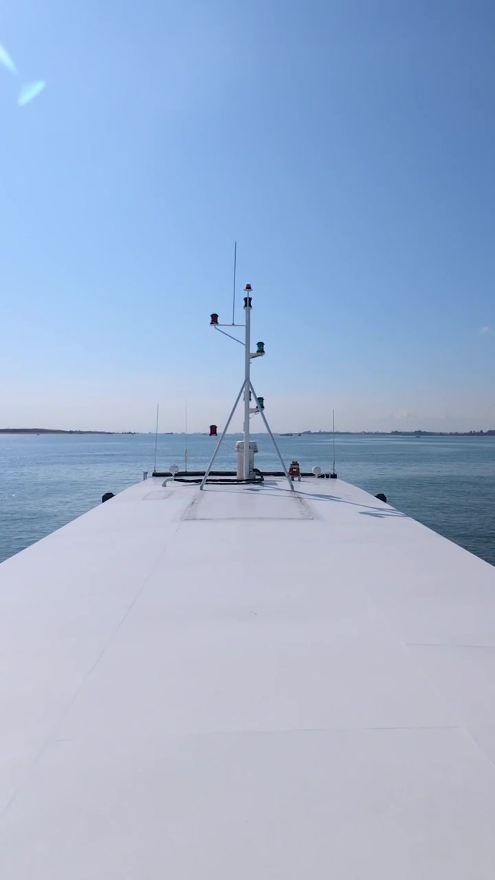 Eine vertikale 9:16-Perspektivaufnahme von einem fahrenden Schiff, die das minimalistische weiße Deck und den weiten blauen Horizont einfängt. Ideal für mobiles Reise-Marketing und industrielles Storytelling in sozialen Medien.