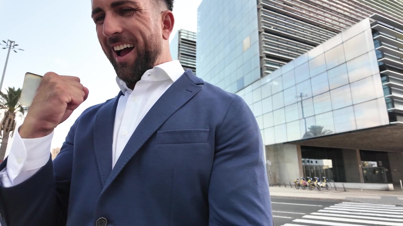 Uomo d'affari che guarda lo smartphone e festeggia una buona notizia