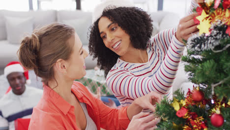 un grupo feliz de amigos diversos decorando el árbol de navidad