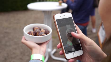 slowmo - young beautiful girl taking a photo of sweet doughnouts with sugar and chocolate at a food festival