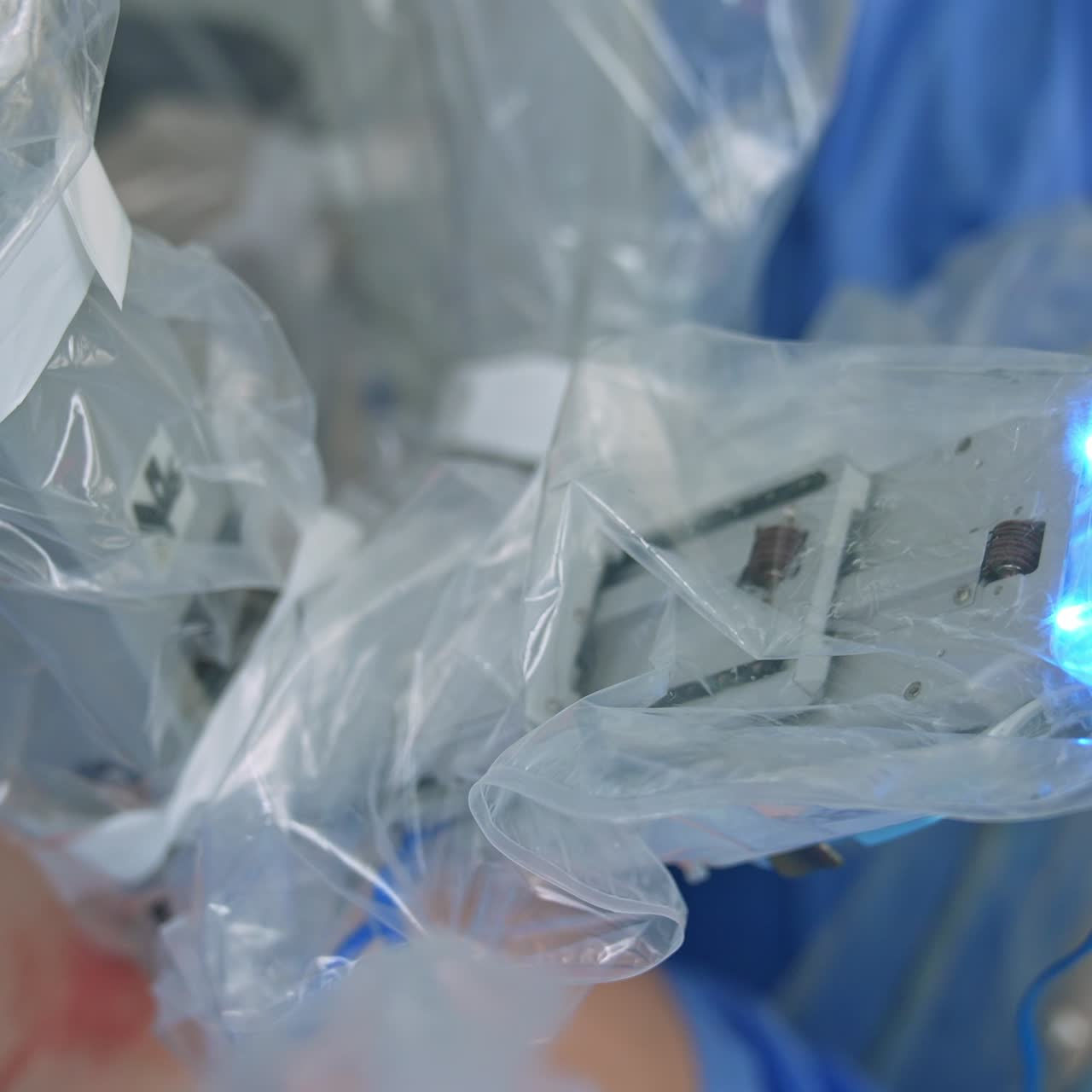 Da Vinci robotic arms coated with plastic for sterility performing operation. High precise equipment moving in the opening in patient's body