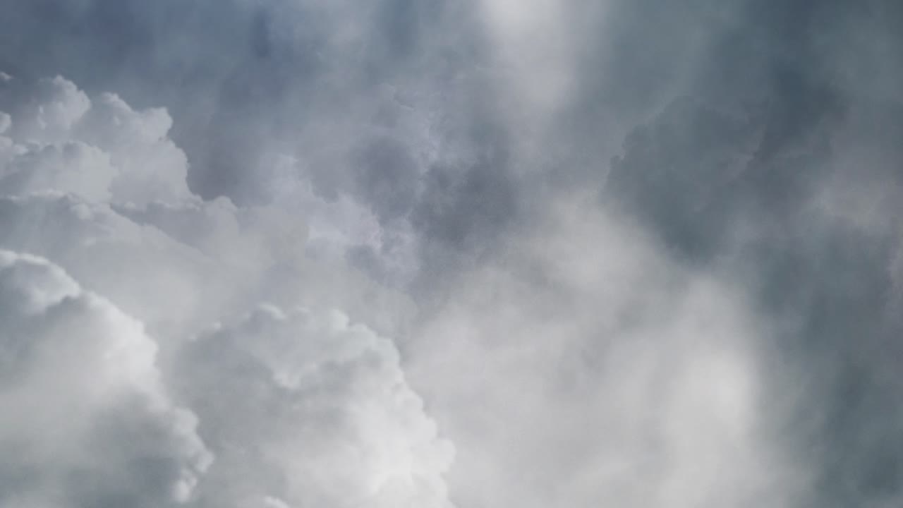 View of wisps of white clouds moving with lightning flashes