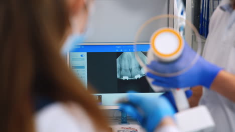 unrecognized teacher is pointing at the screen with x-ray scan of patient's teeth. practice for orthodontic students.