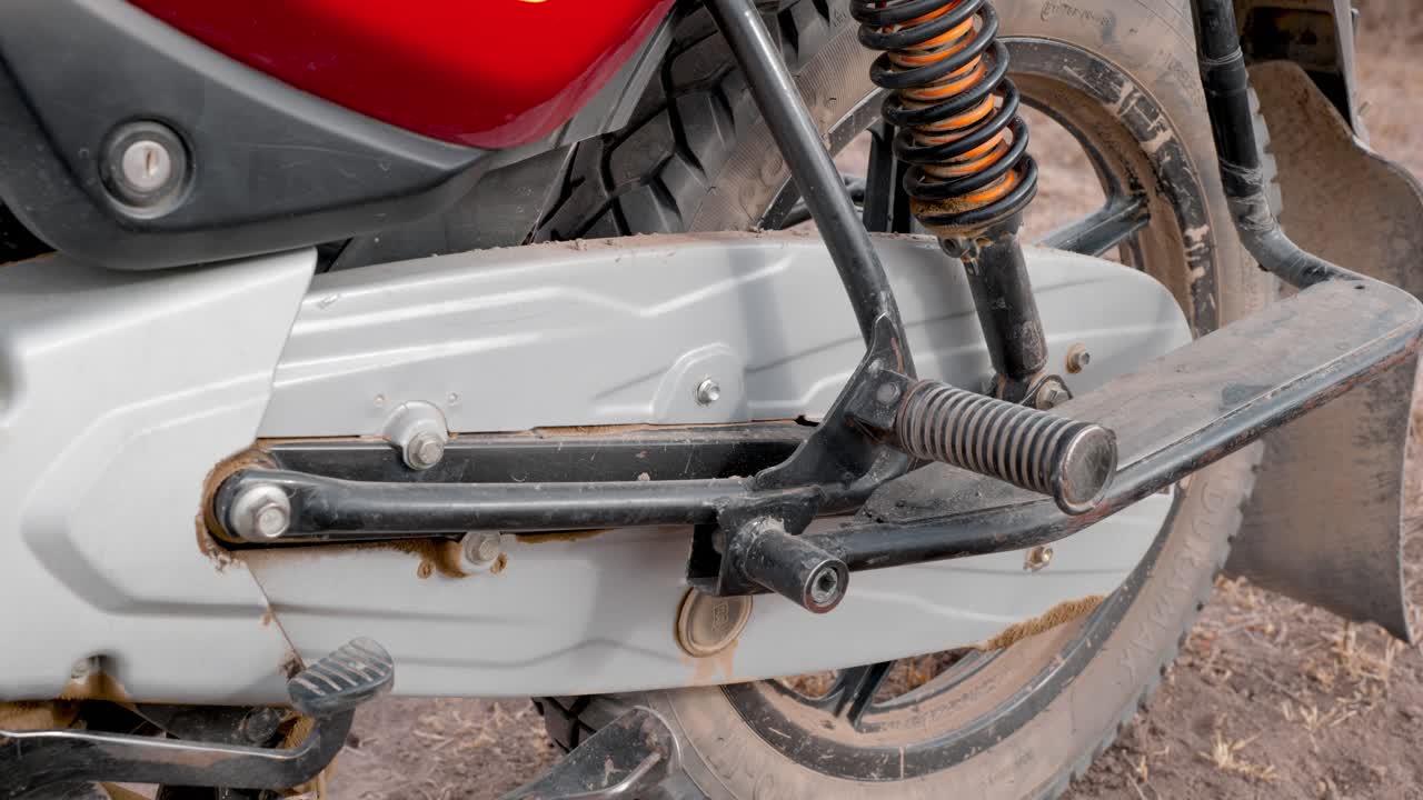 인도에서 아프리카로 수입된 바자즈 오토바이의 뒷바퀴와 체인 가드의 측면 보기를 닫습니다.