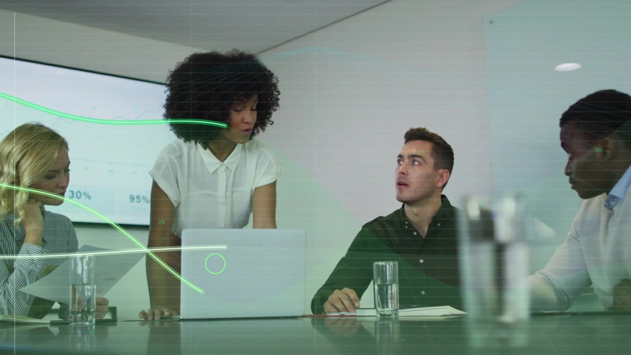 Presenter operating laptop in business meeting causing green data overlay across table, team noting