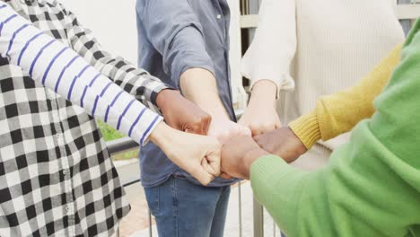 Diverse-male-and-female-business-colleagues-fist-bumping-and-motivating-in-office
