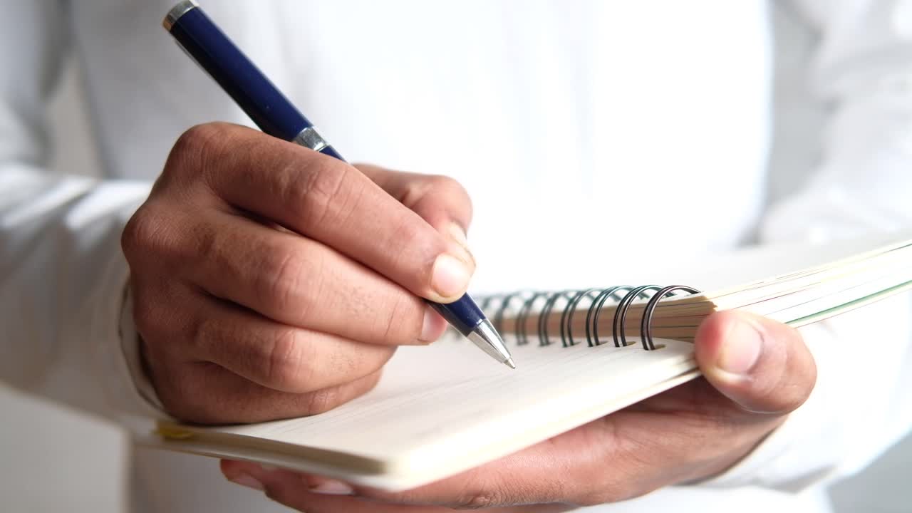 Person Writing in a Spiral Notebook