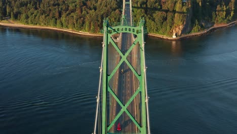 fast aerial drone tilt down close up shot of the traffic and cars driving on lions gate bridge