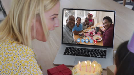 madre y hija caucásicas celebrando su cumpleaños haciendo una videollamada en una computadora portátil en casa