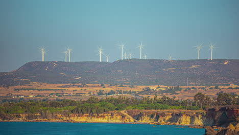 a valley with a lake and a wind turbine field up on a hill in the background