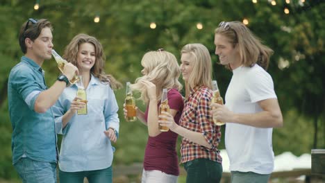 friends having fun and drinking beer, cheering with drinks