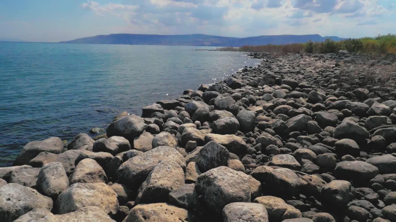 costa aérea baja, roca gris rocosa en un lago azul tranquilo, cámara lenta