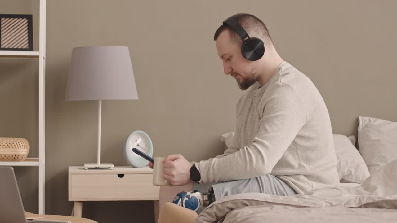 hombre con pierna protésica escuchando música en auriculares en casa