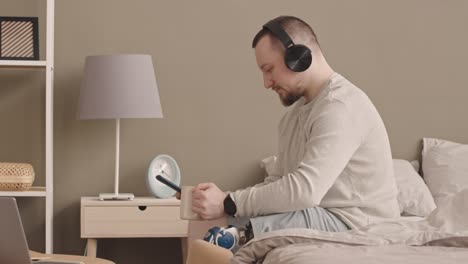 man with prosthetic leg listening to music in headphones at home