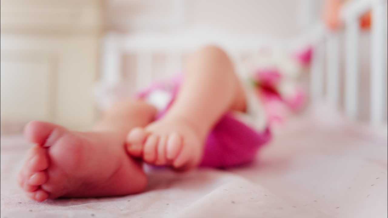 Close up of a baby's feet resting in a crib while wearing a pink outfit