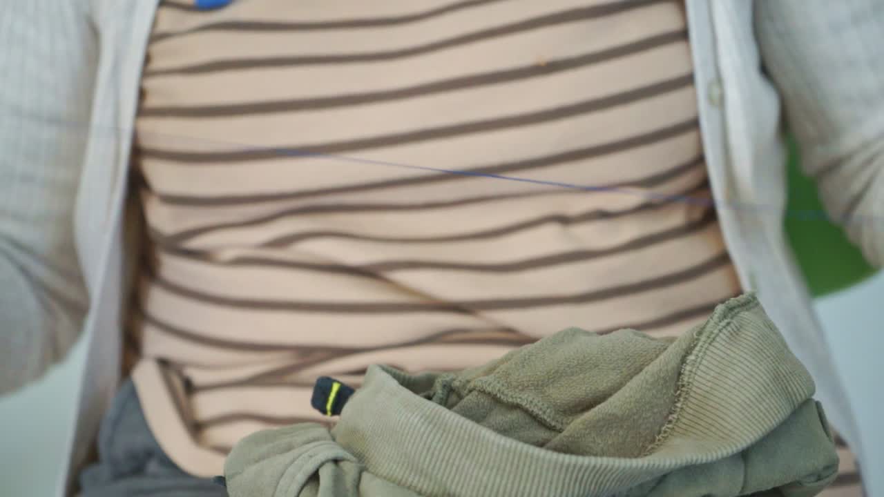 백인 성숙한 할머니는 손자의 바지에 패치를 바느질하고 실에 매듭을 만들고 닫습니다.