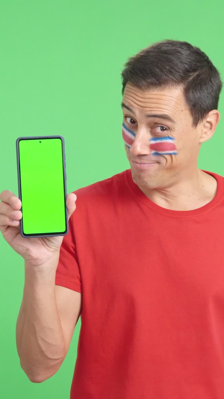 Costa Rican supporter looking at his mobile smiling and showing it