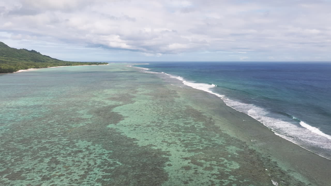Coastline of sandy beach and mountains above fringing reef protecting waters in Rarotonga Cook Islands