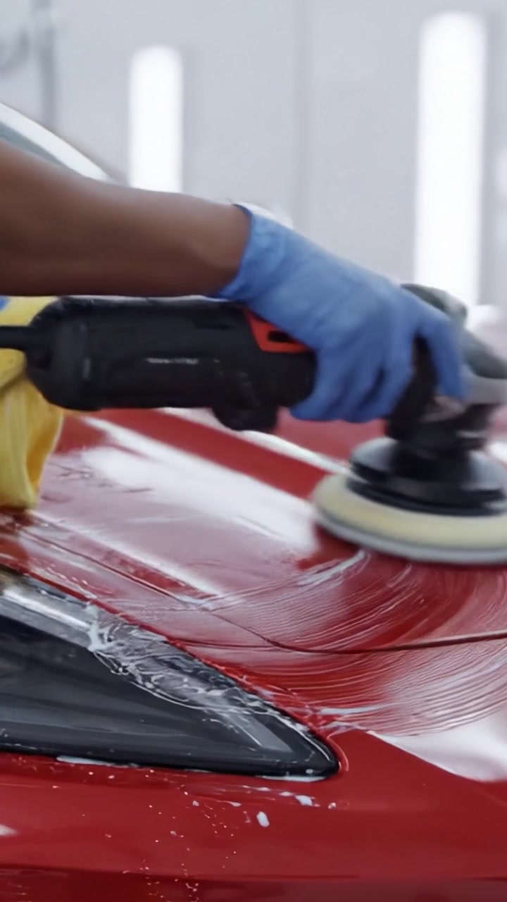 Meticulous Car Detailing Process: Polishing a Glimmering Red Sports Car to Perfection in an Automotive Workshop Environment