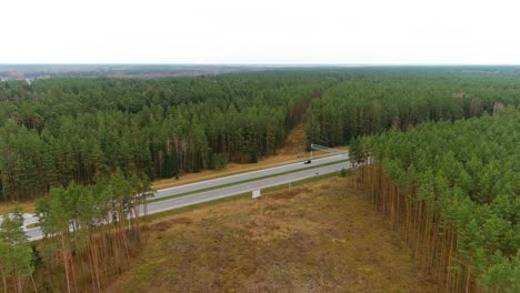 A6-highway-road-in-woodland-area-with-speed-monitoring-device,-aerial-drone-view