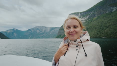 portrait of a happy woman sailing on a cruise ship on a beautiful fjord in norway looks at the camer