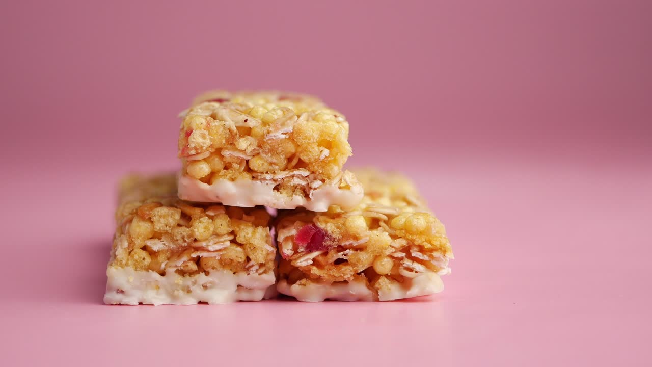 Granola bars stacked on pink surface