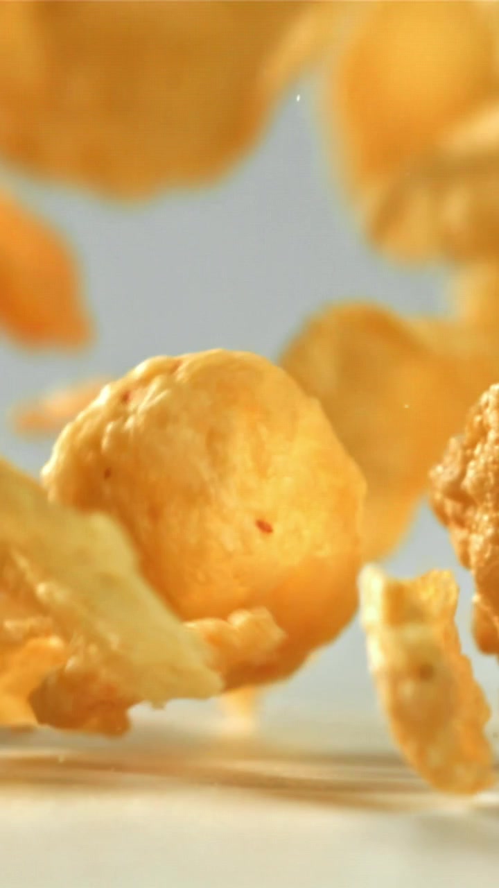 Cornflakes dorati che cadono al rallentatore su una superficie bianca