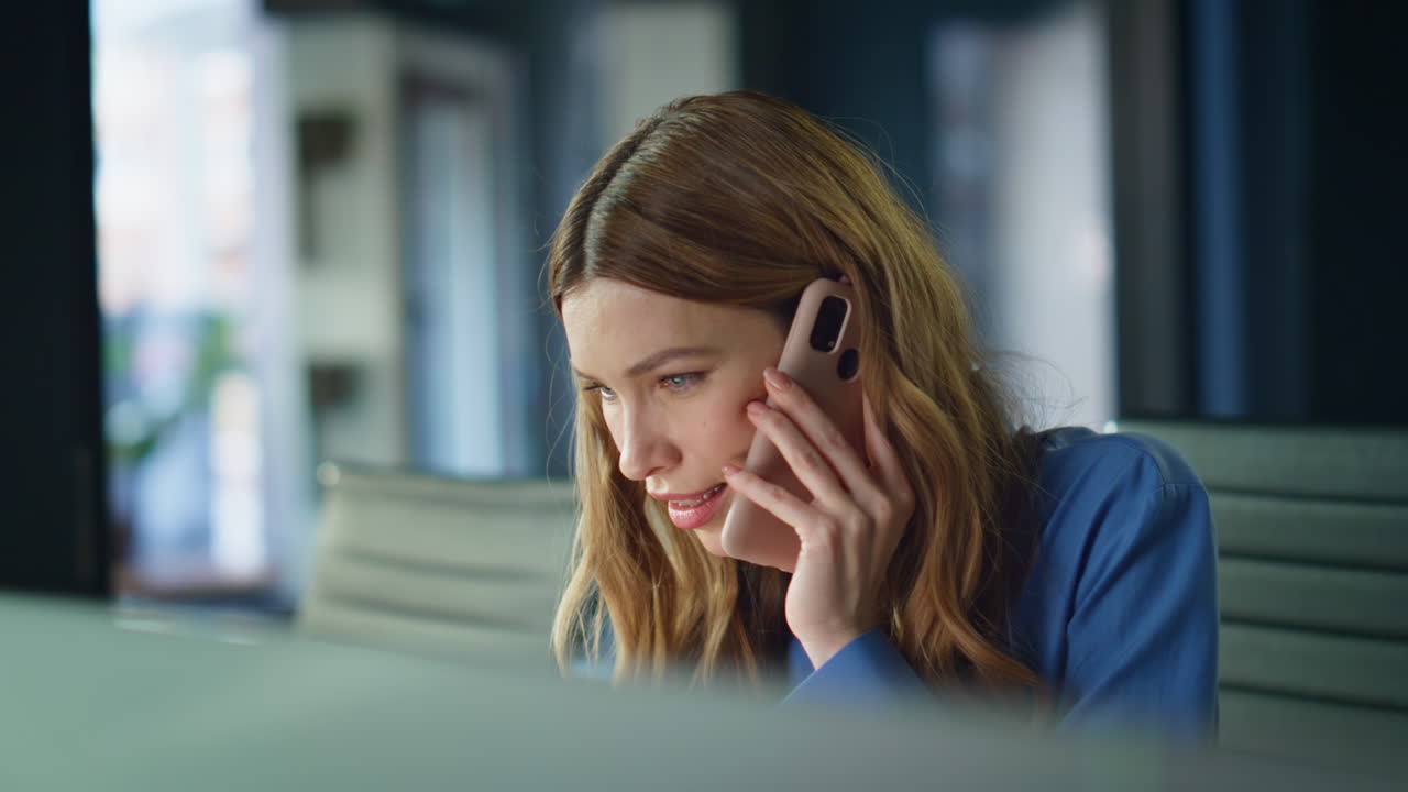 Lady consultant calling mobile phone looking laptop screen at workplace closeup