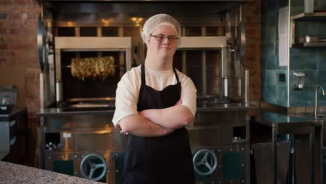 worker with down syndrome with crossed arms standing at doner kebab cafe in apron