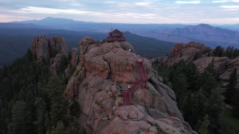 Aerial-View-of-Woman-on-Stairs-Approaching-Devil's-Head-Fire-Spotting-Station-in-Landscape-of-Colorado-USA