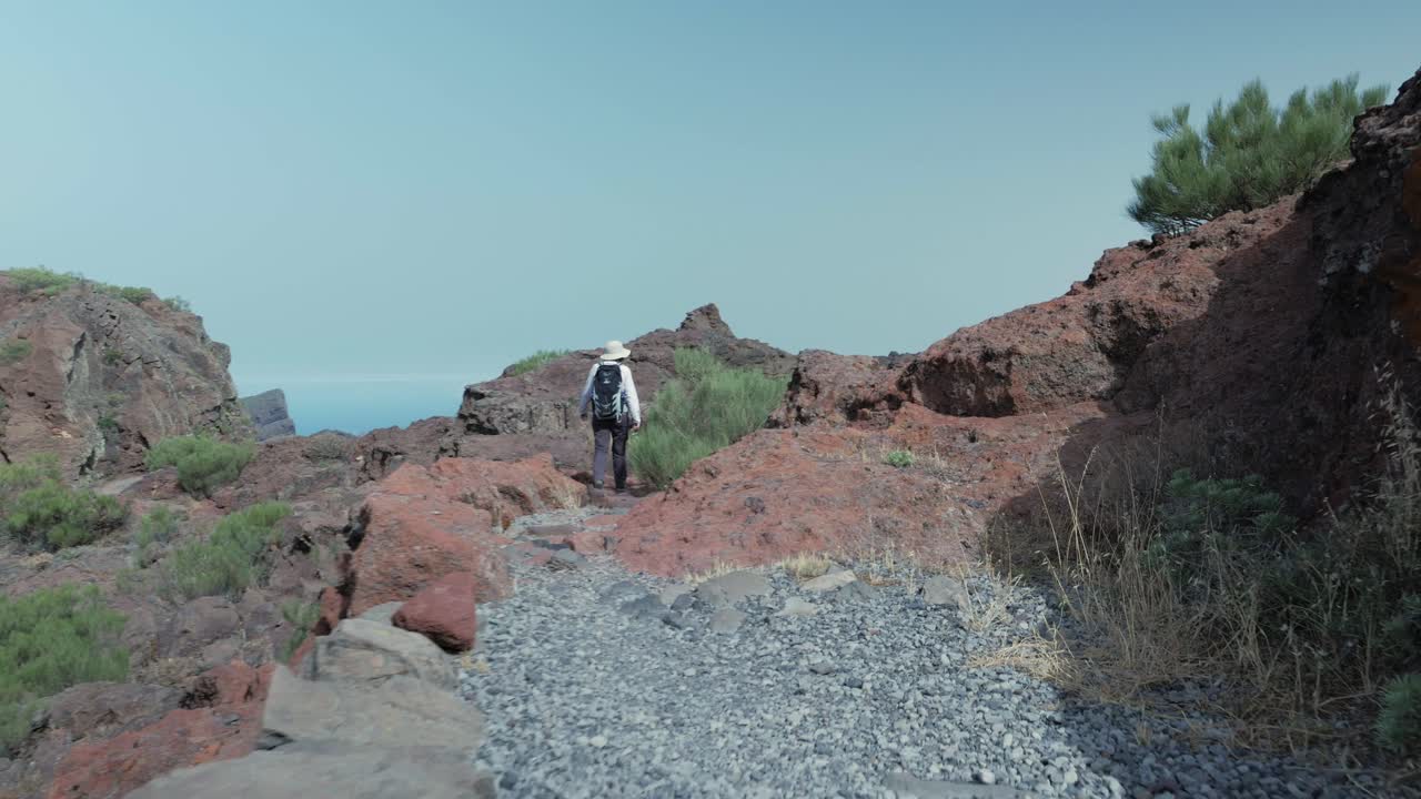 mujer excursionista caminando por un sendero rocoso en las montañas de tenno, tenerife