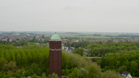 órbita-Aérea-Sobre-La-Famosa-Torre-De-Agua-En-La-Ciudad-De-Axel-Filmada-En-Un-Día-Nublado-Con-El-Panorama-De-La-Ciudad-Detrás