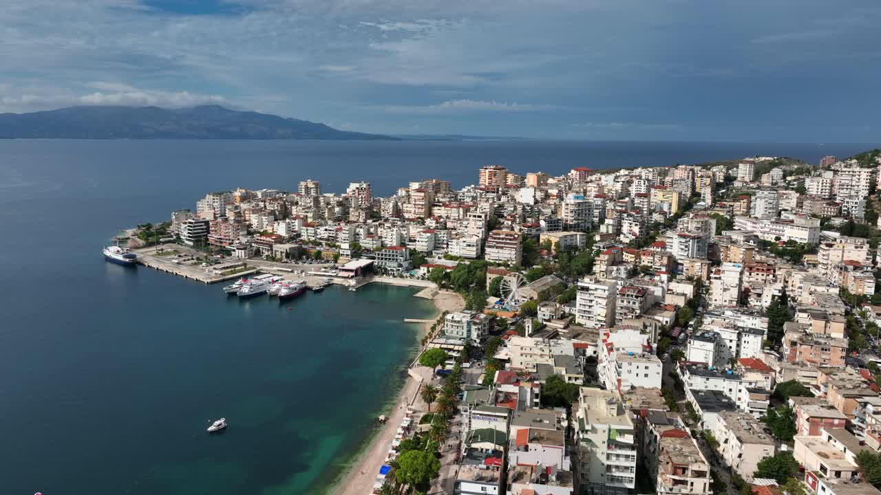 High-angle view of Saranda, Albania, on a bright day, showcasing the coastal city, its buildings, beaches, and the Ionian Sea.
