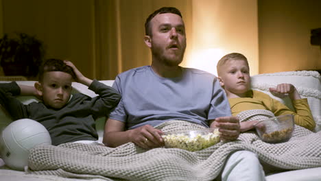 father and sons watching exciting movie