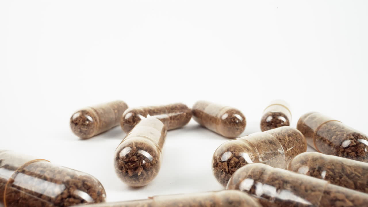 cápsulas transparentes con contenido granulado marrón sobre blanco