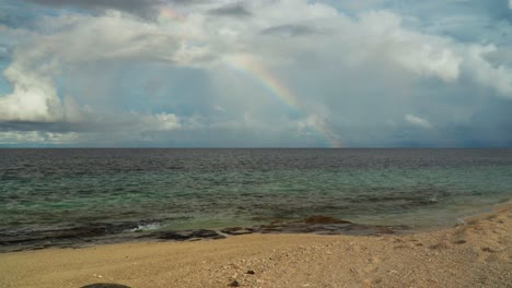 Heavenly-scenery-at-the-beach-with-stunning-colorful-rainbow-above-sea-surface