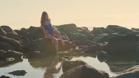 Woman-sitting-on-the-rock-at-the-beach-4k