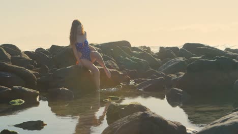 mujer sentada en la roca en la playa 4k