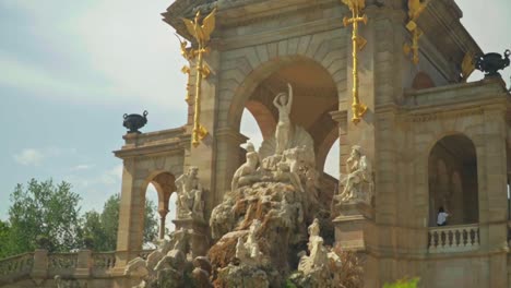 Atemberaubende-Aufnahmen-Eines-Jungen-Kaukasischen-Mädchens-In-Einem-Grünen-Kleid-Und-Hut,-Das-Freudig-Vor-Der-Cascada-Monumental-–-Gaudís-Brunnen-Im-Parc-De-La-Ciutadella-–-Posiert