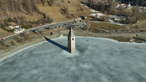 Turistas-Caminando-A-La-Iglesia-Hundida-De-Graun-En-El-Lago-Reschen-En-Un-Frío-Día-De-Invierno