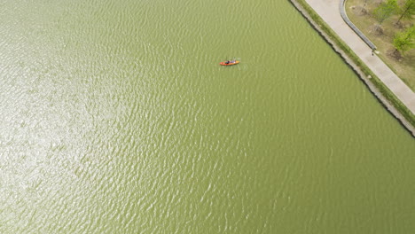 Shelby-farms-park-with-vibrant-green-water,-slight-ripples,-and-land-edge,-aerial-view