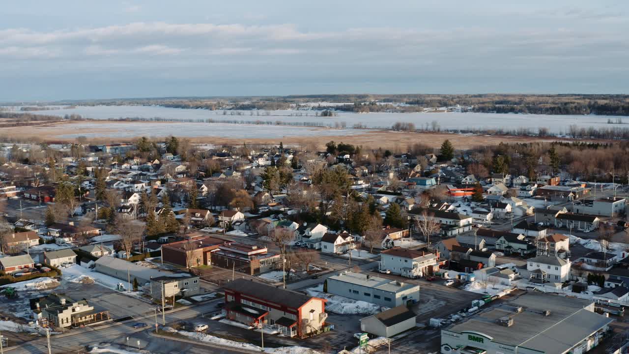 Langsomt luftfoto med venstre dolly-bevægelse af den snedækkede by Thurso, Quebec, Canada, med den frosne Ottawa-flod synlig i baggrunden på en vinterdag