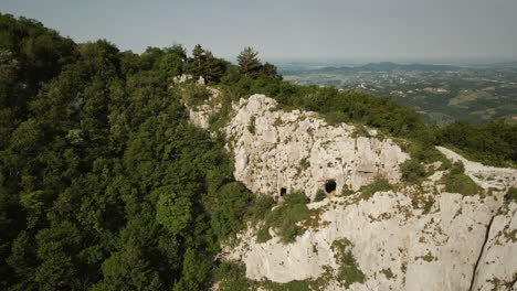 Drone-shot-of-the-mountain-Sabotin-with-the-rocky-side-and-a-green-forest