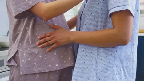 primer plano de una pareja embarazada del mismo sexo bailando juntos en la cocina