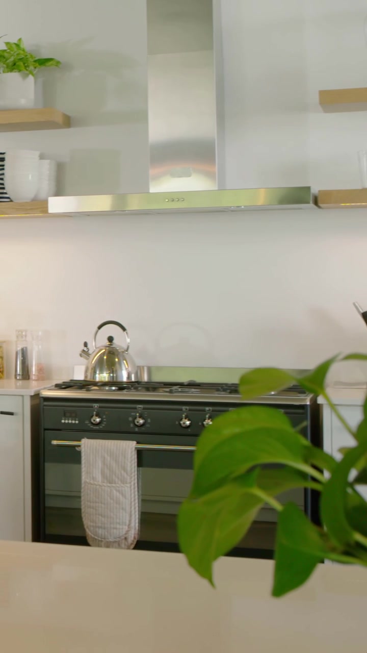 Video verticale: La telecamera panoramica inquadra il fornello e il bancone circostante in una cucina di casa, mostrando un bollitore e una cappa.