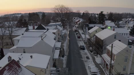 aerial establishing shot of old homes in winter snow along quiet empty street