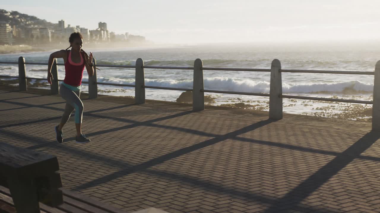 mujer afroamericana corriendo por el paseo marítimo al atardecer