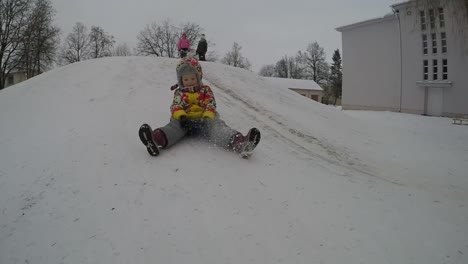 lady child slide down icy hill on plastic disc in winter vacations