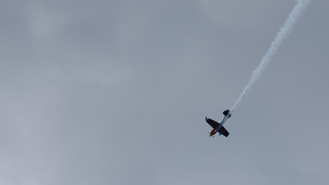 un solo avión ejecutando volteretas aéreas y rastros de humo